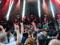 Zespół gra na scenie podczas festiwalu w Jarocinie. Widać publiczność, światła i instrumenty.