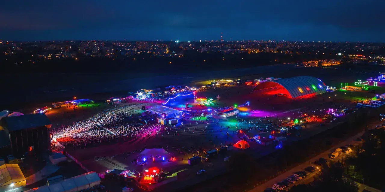 Nocne, kolorowe światła rozświetlają teren festiwalu na powietrzu. Tłumy bawią się pod wielkim, podświetlonym namiotem i na otwartych scenach.