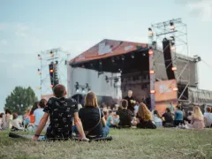 Widownia siedzi na trawie przed sceną podczas Enea Festival Baranowo.