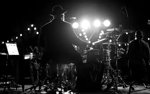 Perkusista w kapeluszu gra na bębnach podczas koncertu MTV Unplugged Polska.