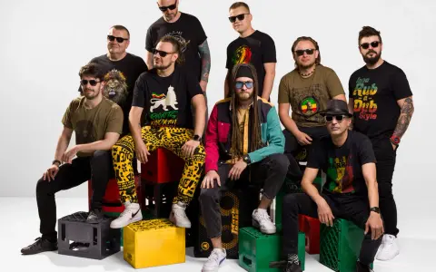 Grupa mężczyzn w koszulkach z motywami nawiązującymi do rastafarianizmu. Jeden z nich ma dredy i kolorową kurtkę, co może kojarzyć się z tym, czym jest rastafarianizm.