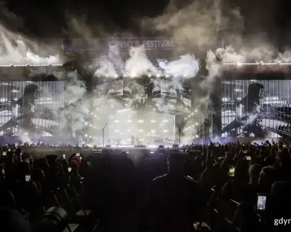 Koncert Linkin Park na Opener Festival. Tłum ludzi z telefonami, dym i światła na scenie.