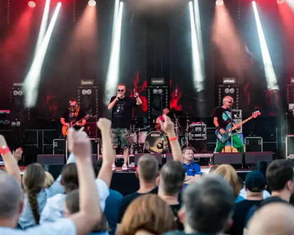 Zespół gra na scenie podczas festiwalu w Jarocinie. Widać publiczność, światła i instrumenty.