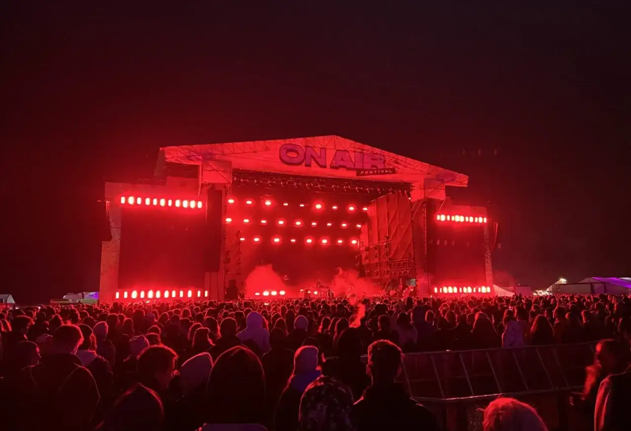 Tłum ludzi na festiwalu ON AIR, rozświetlony czerwonymi światłami sceny.