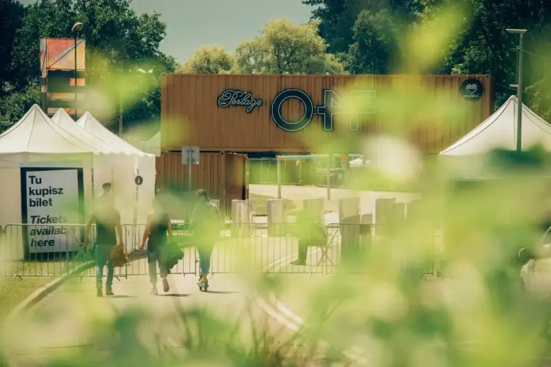 Ludzie idą po bilety na OFF festival. W tle widać logotyp festiwalu.
